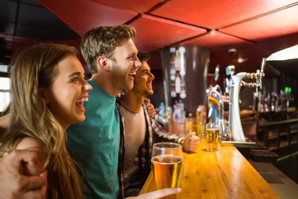 Smiling brown hair standing with arm around his friends — Stock Photo, Image