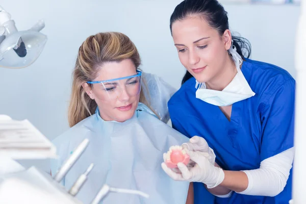 Dentist showing patient model of teeth — Stock Photo, Image