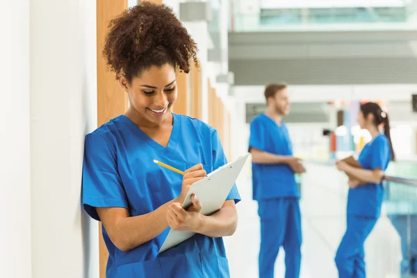 Medical student taking notes in hallway — Stock Photo, Image