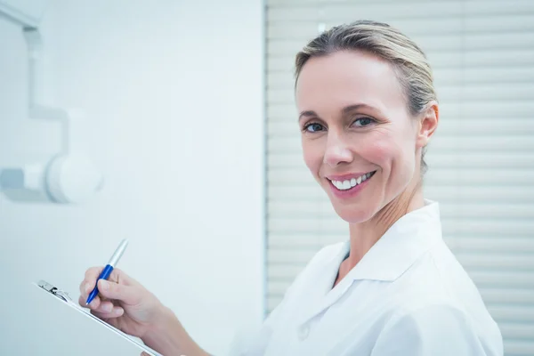 Sorridente dentista femminile che tiene appunti — Foto Stock