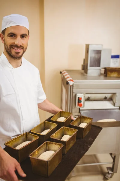 Happy baker holding tray of loaf tins — Stock Photo, Image