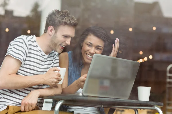 Amigos sorridentes com uma bebida quente usando laptop — Fotografia de Stock