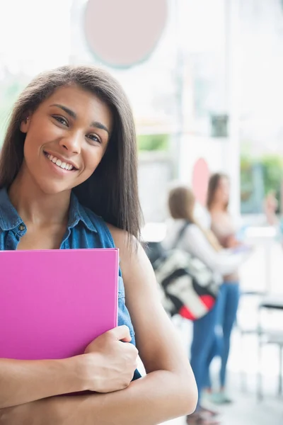 Estudante bonito sorrindo e segurando blocos de notas — Fotografia de Stock