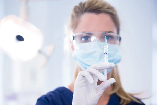 Dentista em máscara e luva segurando uma injeção — Fotografia de Stock