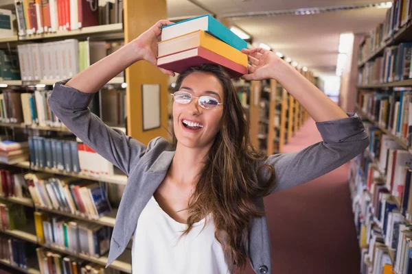 Estudante bonito segurando livros na biblioteca — Fotografia de Stock