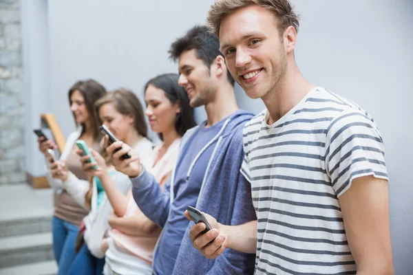 Students using their smartphones in a row — Stock Photo, Image