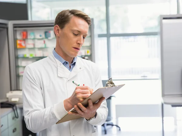 Knappe apotheker schrijven op Klembord — Stockfoto