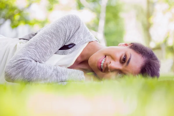 Hezká brunetka ležící na trávě — Stock fotografie