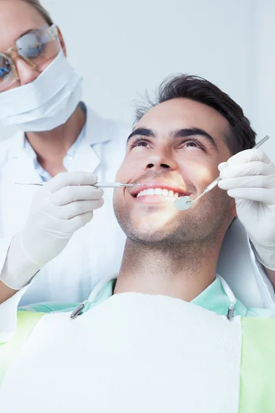 Dentista femminile esaminando denti mans — Foto Stock