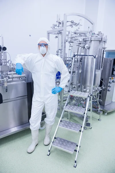 Scientist in protective suit leaning against machine — Stock Photo, Image