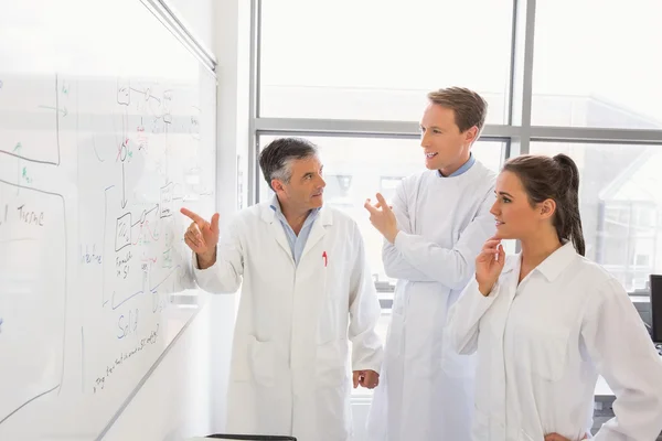 Science students and lecturer looking at whiteboard — Stock Photo, Image