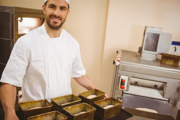 Happy baker holding tray of loaf tins — Stock Photo, Image