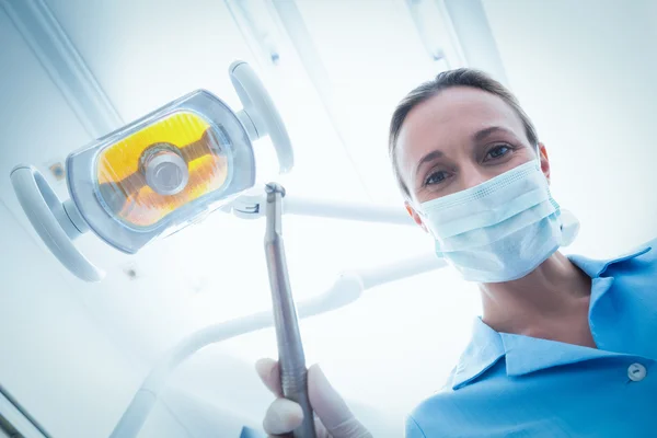 Dentista femenina en máscara quirúrgica sosteniendo herramienta dental —  Fotos de Stock