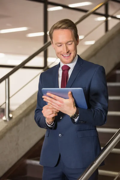 Handsome businessman standing on steps using tablet — Stock Photo, Image