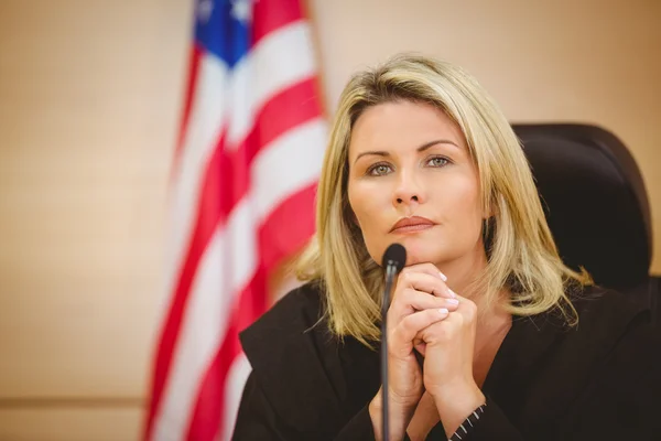 Porträt einer seriösen Richterin mit amerikanischer Flagge im Rücken — Stockfoto