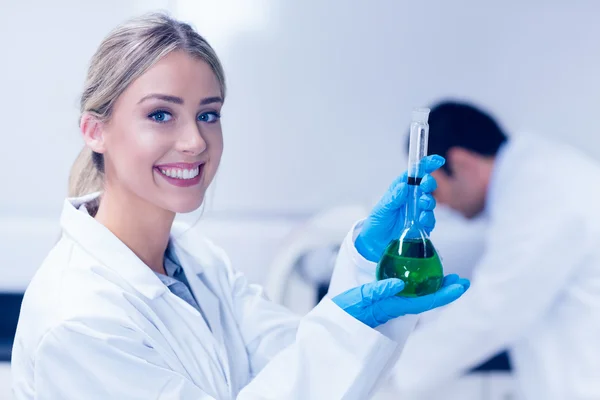 Naturwissenschaftsstudent hält grüne Chemikalie im Becher — Stockfoto