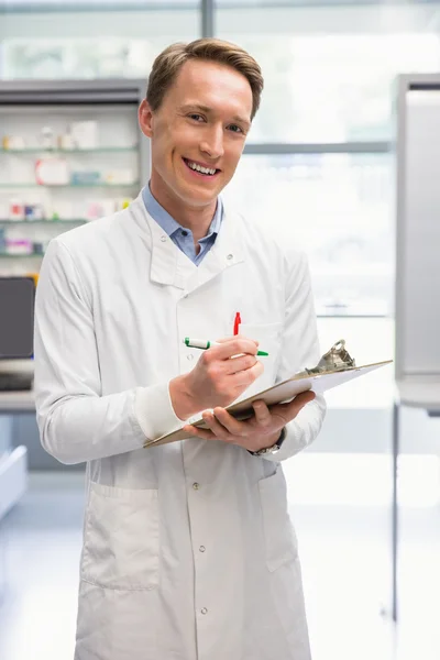 Schöner Apotheker, der auf Klemmbrett schreibt — Stockfoto