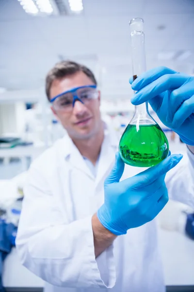 Kemist håller upp bägare grön kemiska — Stockfoto