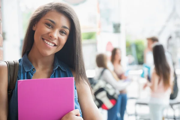 Estudante bonito sorrindo e segurando blocos de notas — Fotografia de Stock