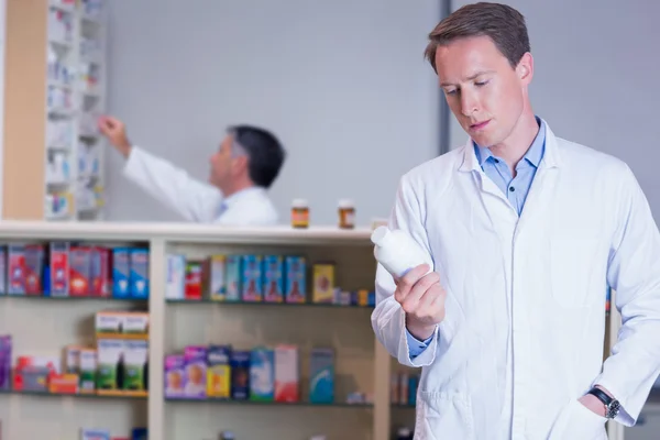 Apotheker liest Etikett auf Medikamentendose — Stockfoto