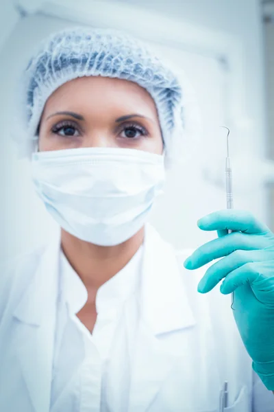 Жінка-стоматолог в хірургічній масці тримає гачок — стокове фото