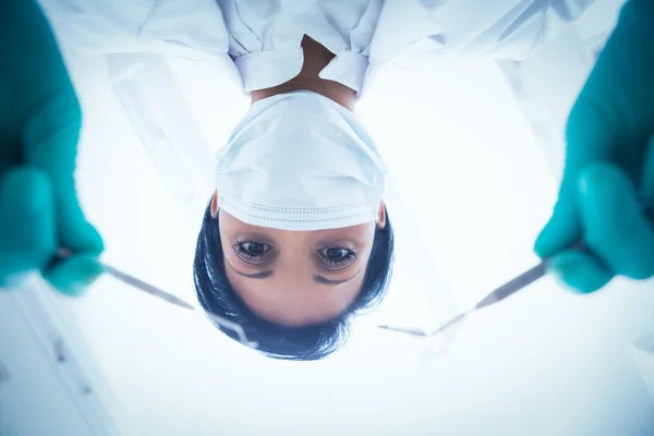 Dentista feminina em máscara cirúrgica segurando ferramentas dentárias — Fotografia de Stock