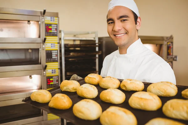 Baker smiling at camera holding tray of rolls — Stock Photo, Image