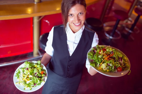 Jolies barmaid tenant des assiettes de salades — Photo