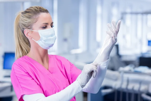 Tandheelkundige in masker trekken op handschoenen — Stockfoto