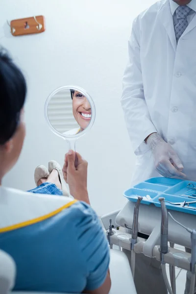Smiling young woman looking at mirror — Stock Photo, Image
