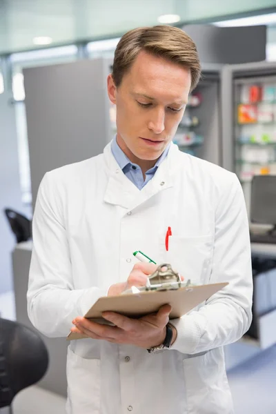 Guapo farmacéutico escribiendo en portapapeles — Foto de Stock