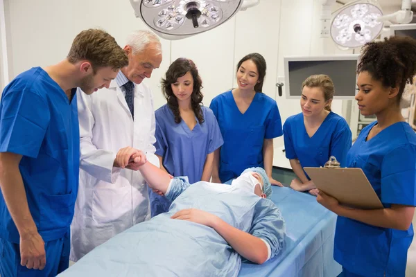 Медицинские студенты и профессор проверяют пульс — стоковое фото