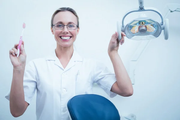 Sorridente dentista femminile in possesso di spazzolino da denti — Foto Stock