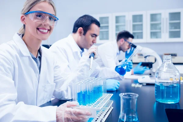 Science student using pipette in the lab to fill test tubes — Stock Photo, Image