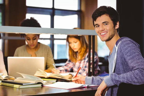 Student tittar på kameran med sina klasskamrater bakom honom — Stockfoto