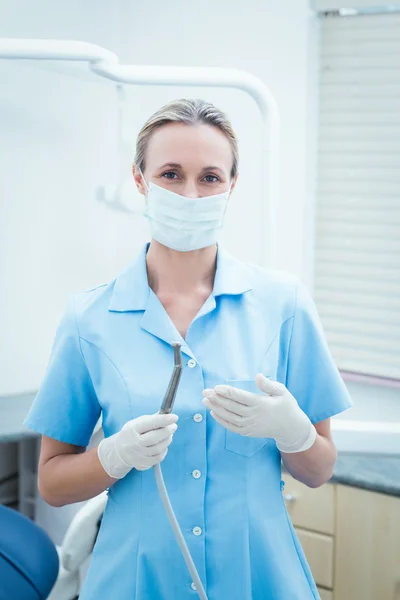 Dentista femenina en máscara quirúrgica sosteniendo herramienta dental —  Fotos de Stock