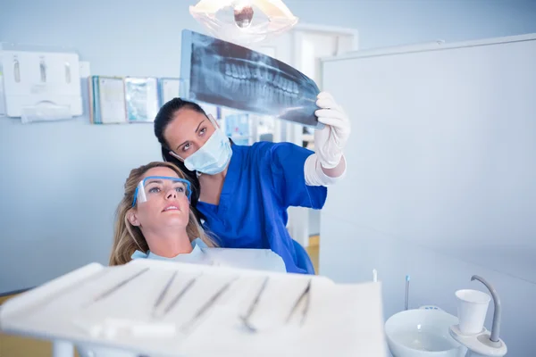 Dentista con máscara explicando radiografía al paciente — Foto de Stock