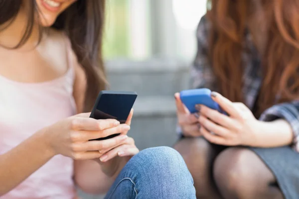 Estudiantes usando sus teléfonos inteligentes juntos — Foto de Stock