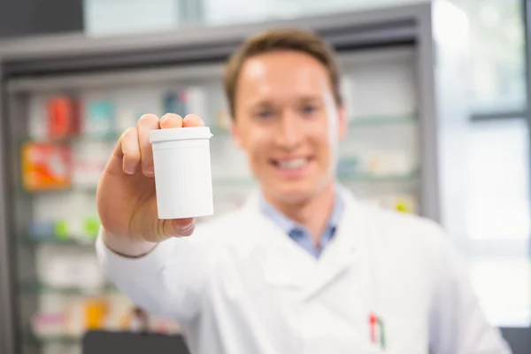 Красивый фармацевт показывает банку с лекарствами — стоковое фото