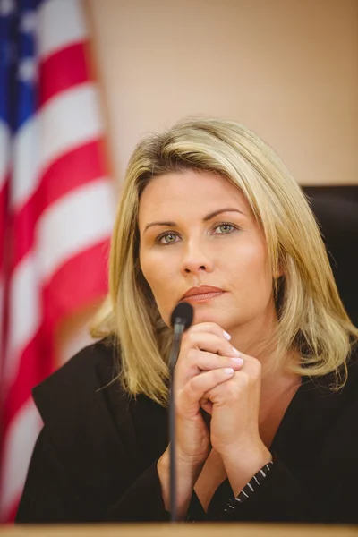 Portrait of a serious judge with american flag behind her