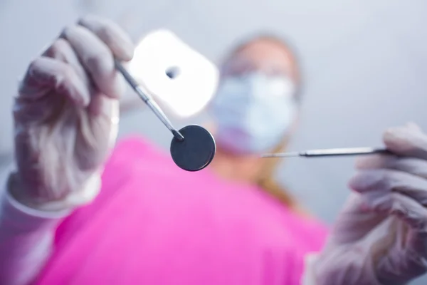 Dentista em máscara cirúrgica segurando ferramentas sobre o paciente — Fotografia de Stock