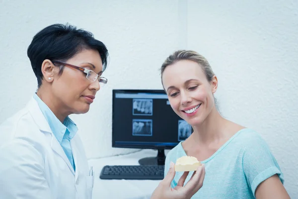Дантист показывает женские протезные зубы — стоковое фото