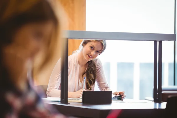 Smiling student sitting next to the window taking notes — Stock Photo, Image