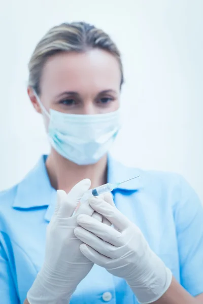 Dentista feminina em máscara cirúrgica segurando injeção — Fotografia de Stock