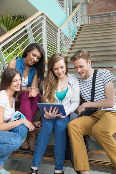 Estudiantes sonrientes sentados en escalones con tablet pc — Foto de Stock