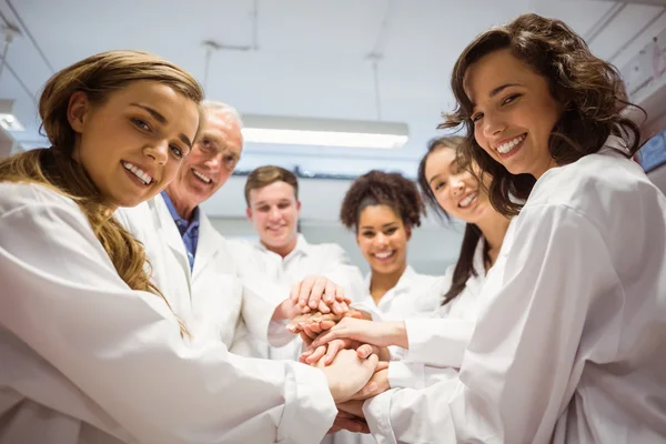 Science students and lecturer putting hands together — Stock Photo, Image