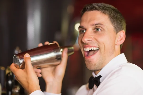 Симпатичный бармен, улыбающийся в камеру и делающий коктейль — стоковое фото