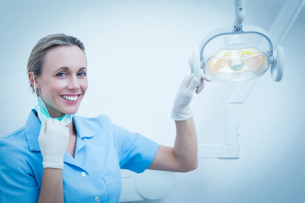 Sonriente dentista hembra ajustando la luz —  Fotos de Stock