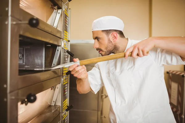 Пекарь берет хлеб из духовки — стоковое фото