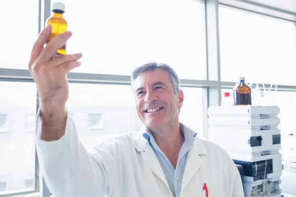 Científico con bata de laboratorio sosteniendo una botella química — Foto de Stock